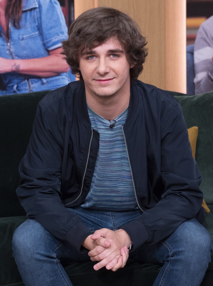 a young man is sitting on a couch with his hands folded