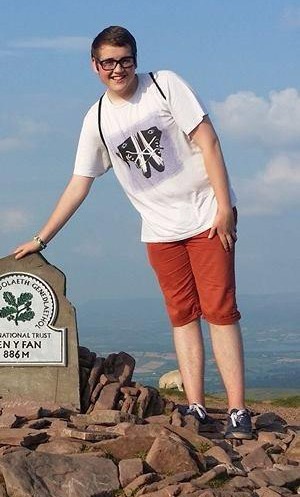 a young man is standing on top of a rocky hill .