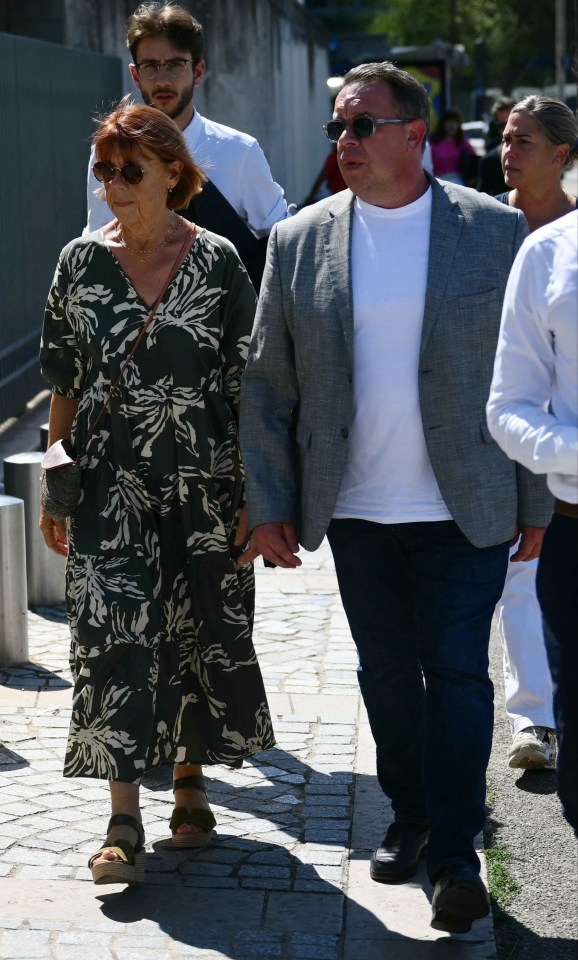 a man and woman walking down a sidewalk holding hands