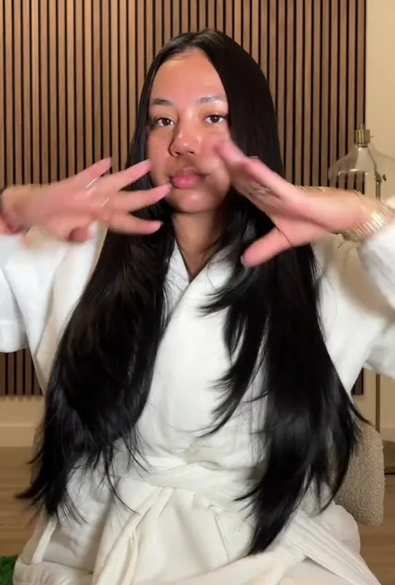 a woman in a white robe is covering her face with her hands