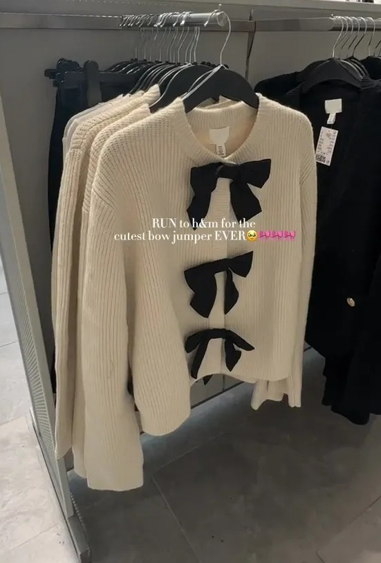 a white sweater with black bows is on display in a store