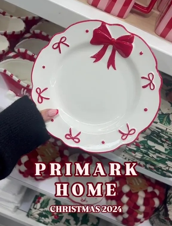 a person is holding a white plate with a red bow and the words primark home christmas 2024