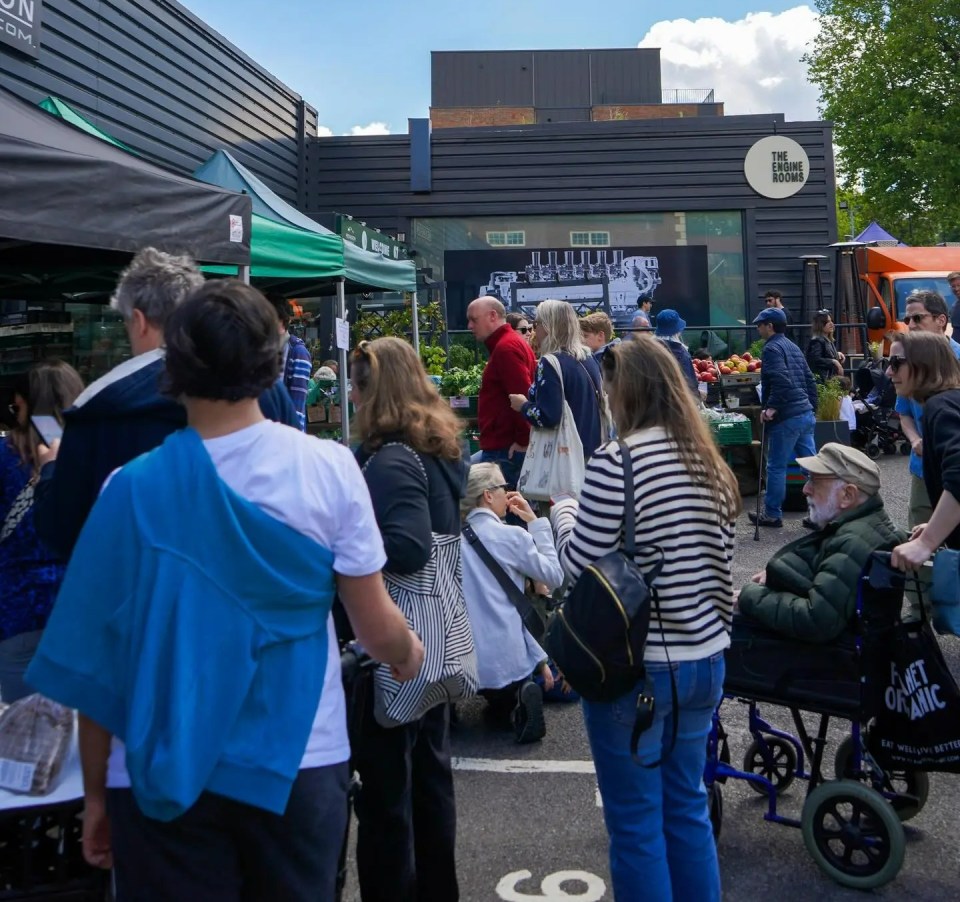 a crowd of people are gathered in front of a building that has a sign on it that says ' the market '