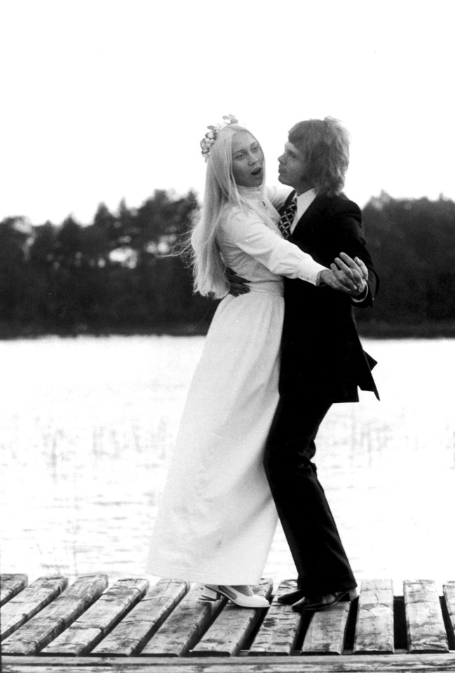 a black and white photo of a bride and groom on a dock