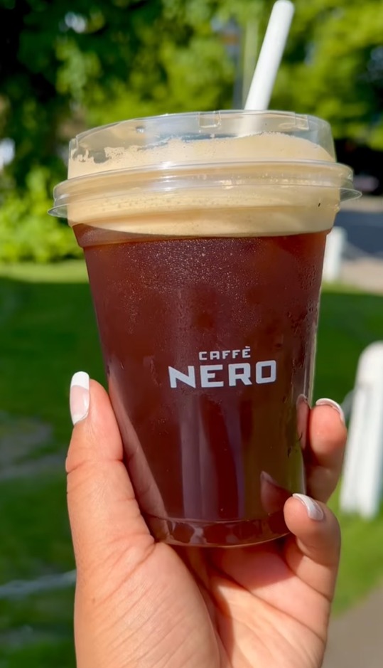 a person is holding a cup of caffe nero