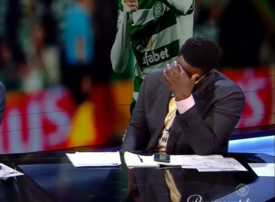 a man in a suit is covering his face in front of a celtic player wearing an dafabet jersey