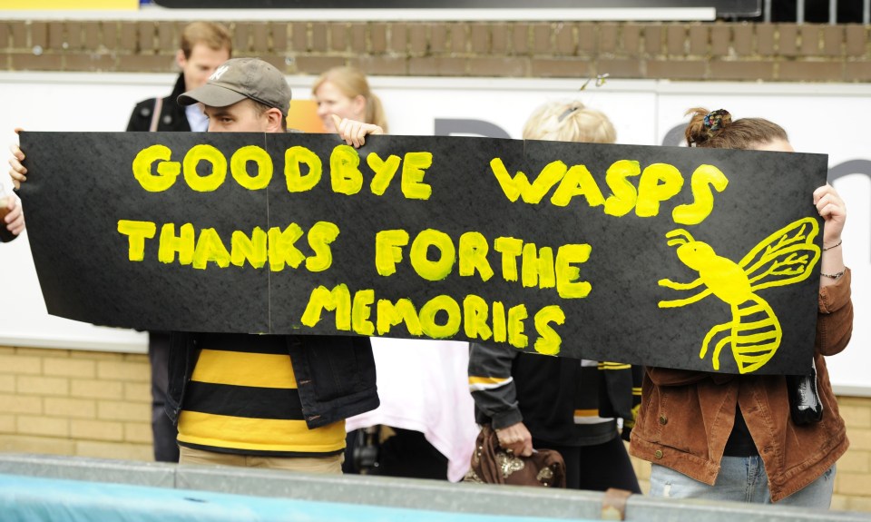 a man holding a sign that says goodbye wasps thanks for the memories