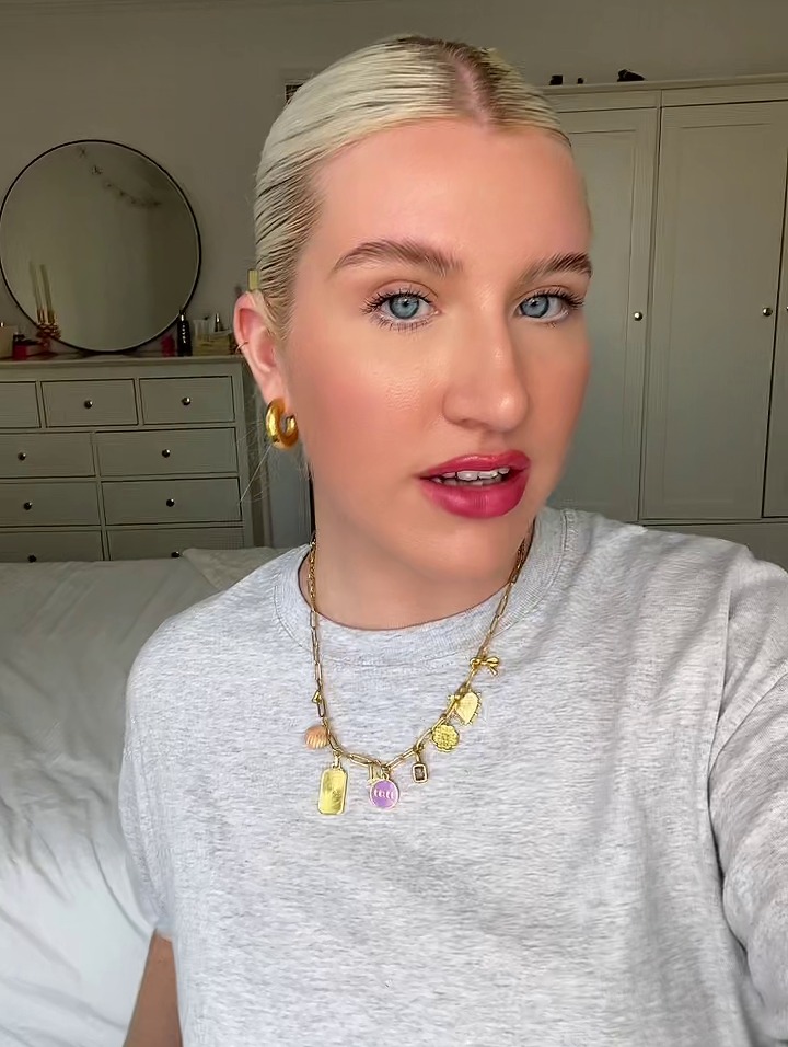 a woman wearing a grey t-shirt and a gold necklace