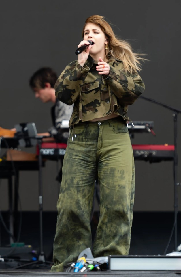 a woman in a camo jacket sings into a microphone