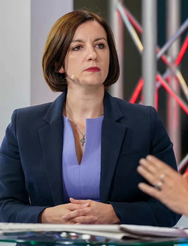 a woman sitting at a table with her hands folded