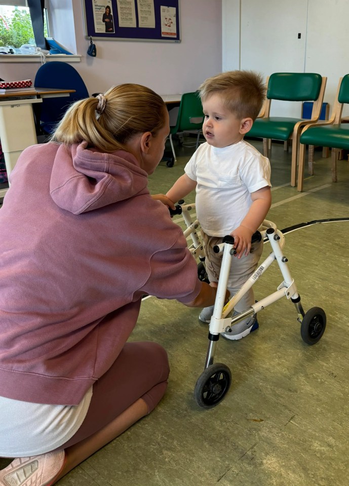 a little boy in a walker is being helped by a woman