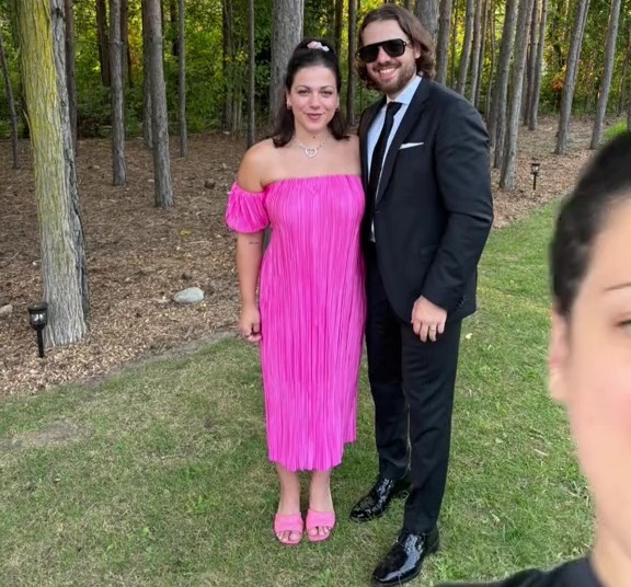 a man in a suit stands next to a woman in a pink dress