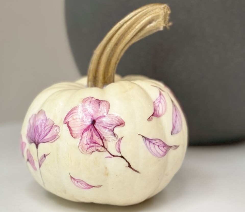 a white pumpkin with pink flowers painted on it