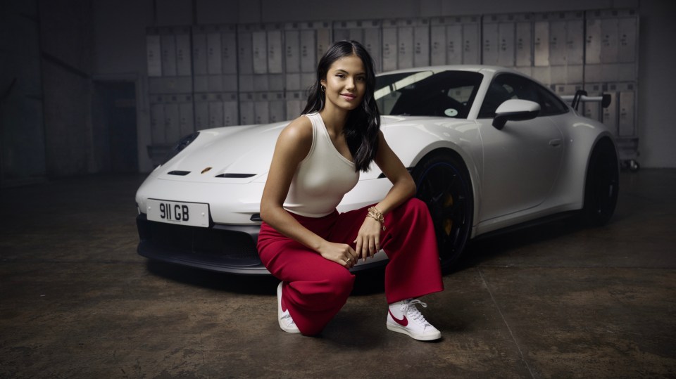 a woman kneeling in front of a white porsche 911 gt3