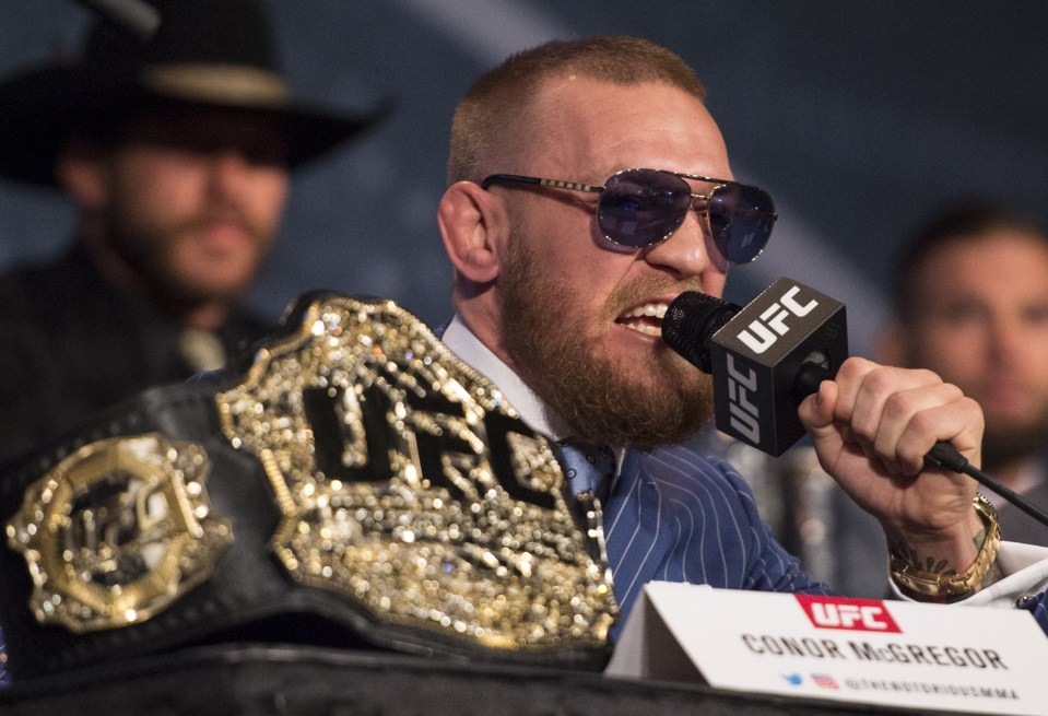 a man wearing sunglasses is speaking into a ufc microphone