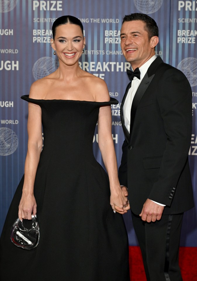 a woman in a black dress and a man in a tuxedo hold hands on a red carpet