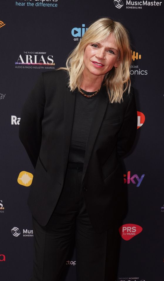 a woman in a black suit stands on a red carpet that says arias