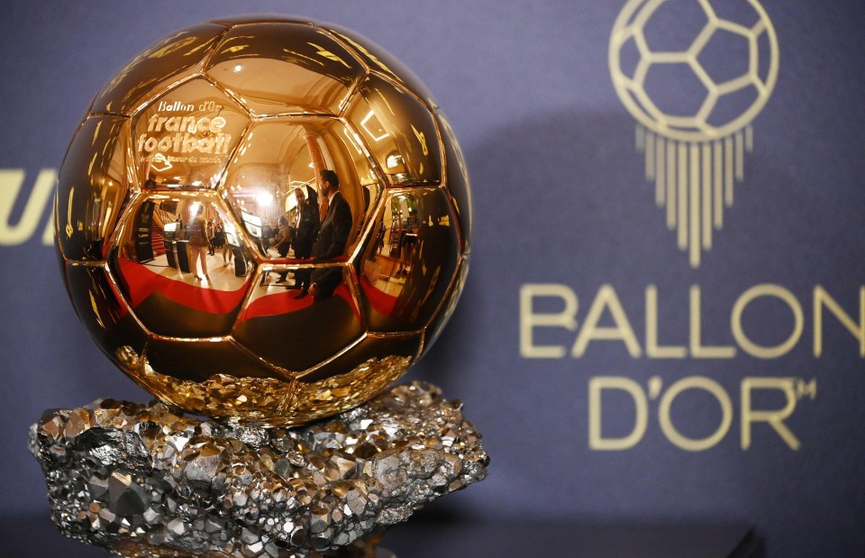 a golden soccer ball is sitting on a rock in front of a sign that says ballon d' or