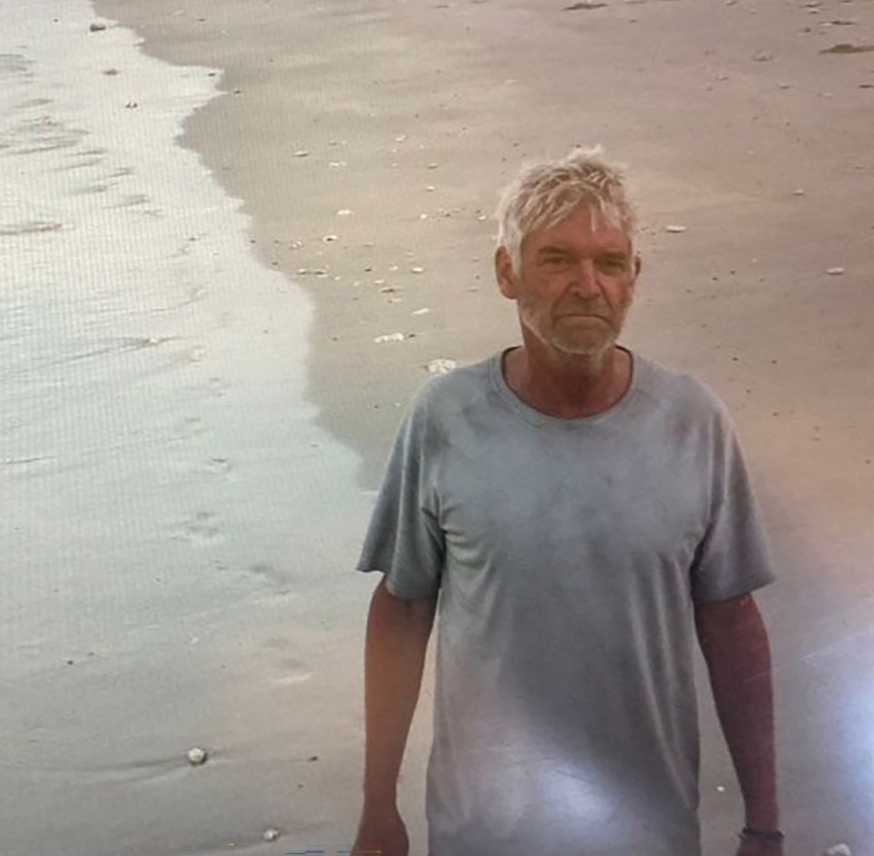 a man in a grey shirt stands on a beach