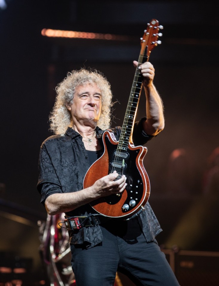 a man with curly hair is playing a guitar on a stage