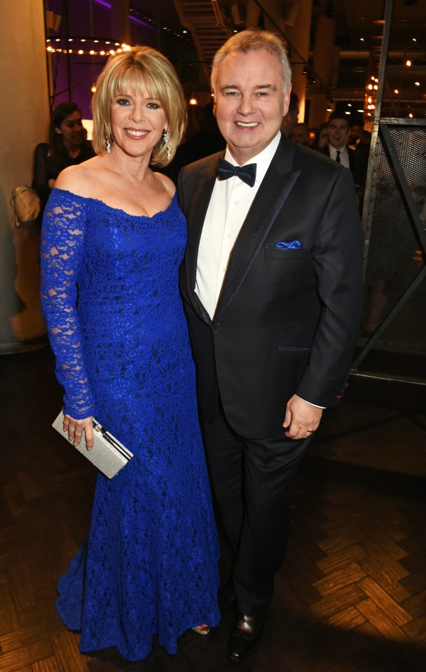 a woman in a blue lace dress stands next to a man in a tuxedo