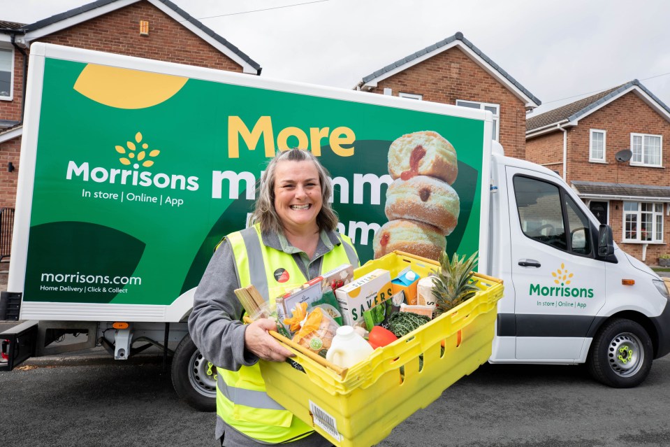 a woman is holding a basket of food in front of a morrisons truck