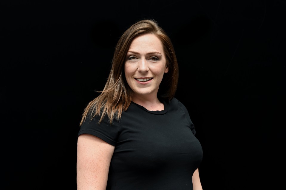 a woman in a black shirt smiles in front of a black background