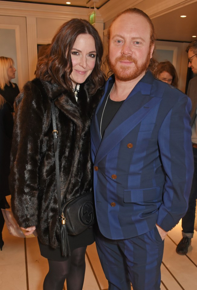 a man in a blue suit stands next to a woman in a fur coat