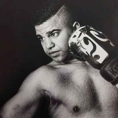 a black and white photo of a shirtless boxer wearing boxing gloves .