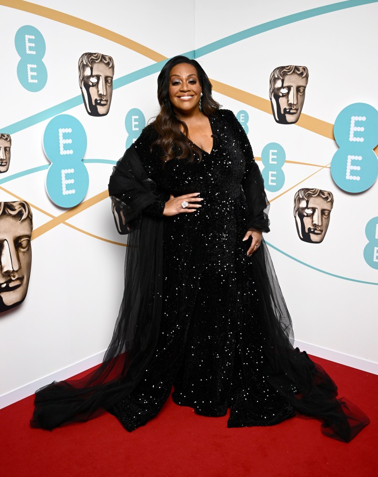 a woman in a black dress stands on a red carpet