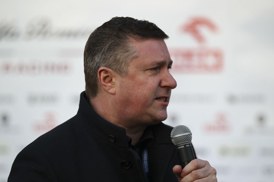 a man speaking into a shure microphone in front of a white background