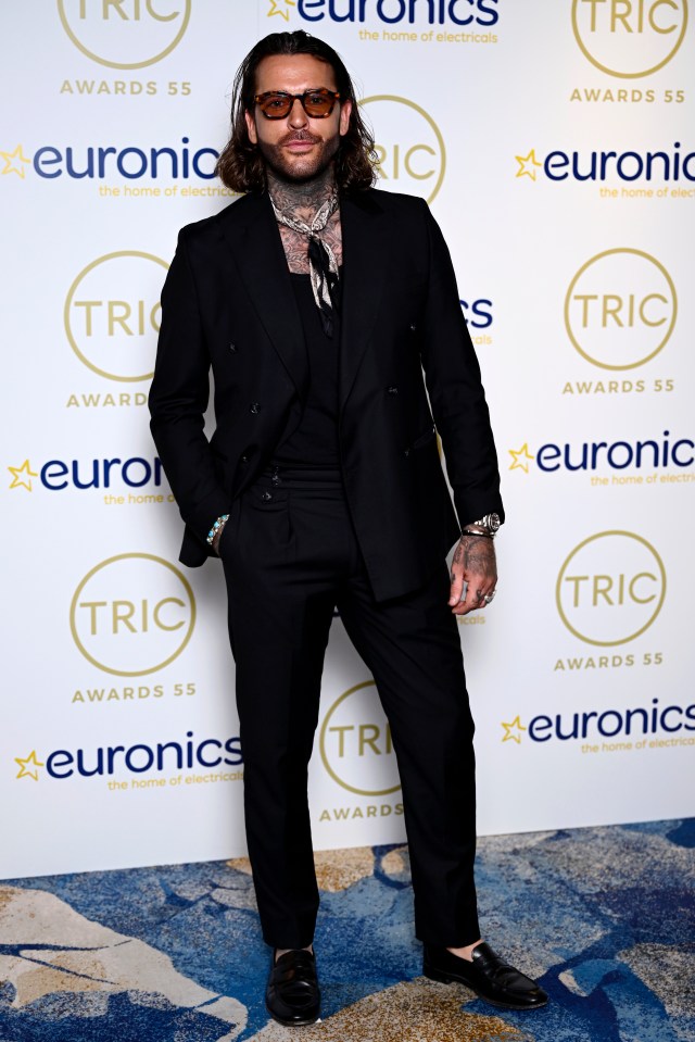 a man in a suit stands in front of a wall that says euronics