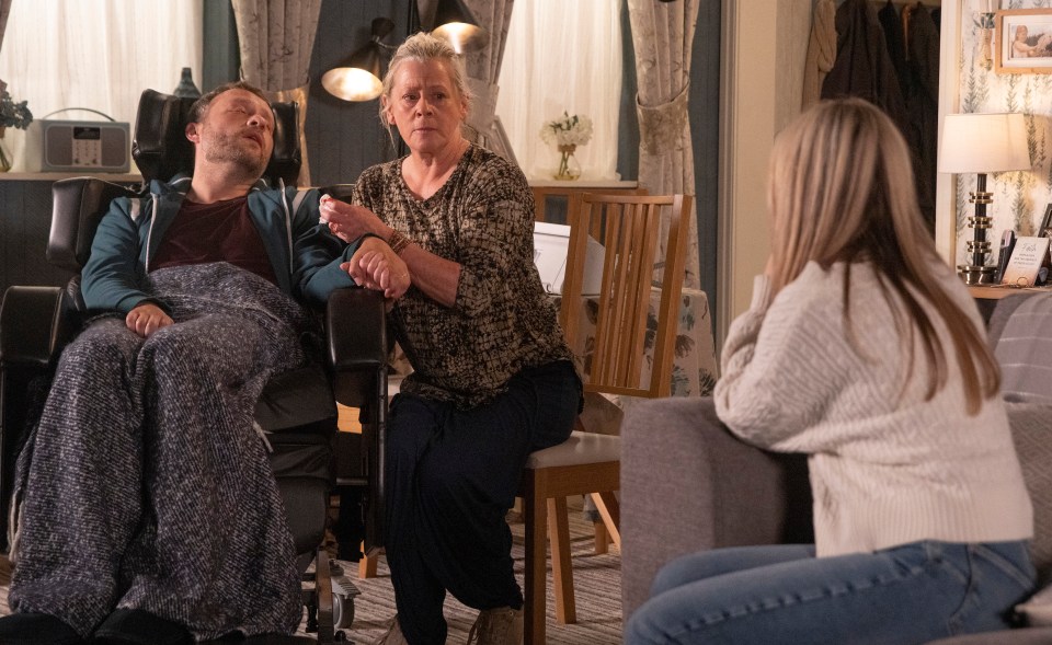 a man in a wheelchair is being comforted by two women