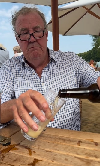 a man sitting at a table pouring beer into a glass