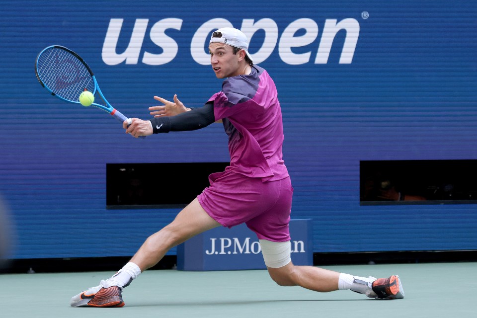 a man playing tennis in front of a sign that says us open