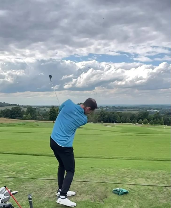 a man in a blue shirt is swinging a golf club