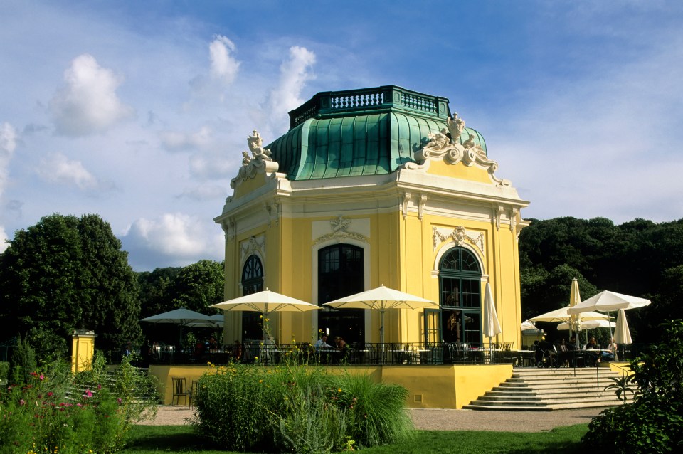 a yellow building with a green roof and umbrellas in front of it