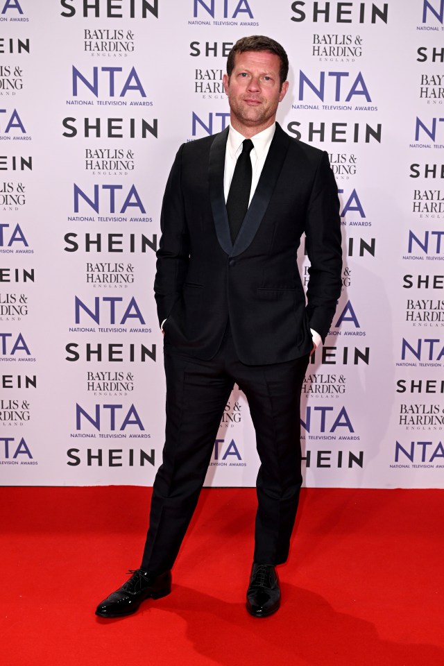 a man in a suit stands in front of a wall that says shein