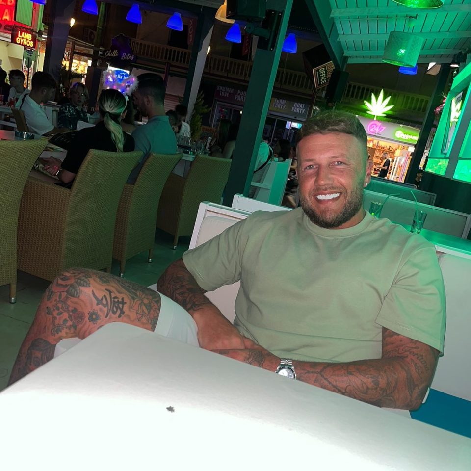 a man sits at a table in front of a sign that says cafe