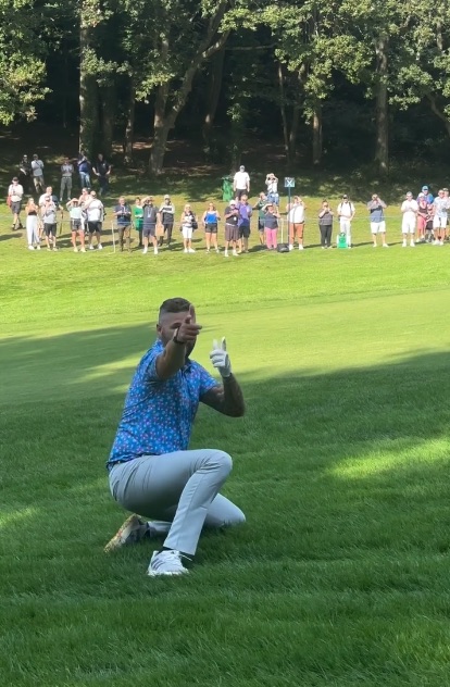 a man in a blue shirt is kneeling on a golf course