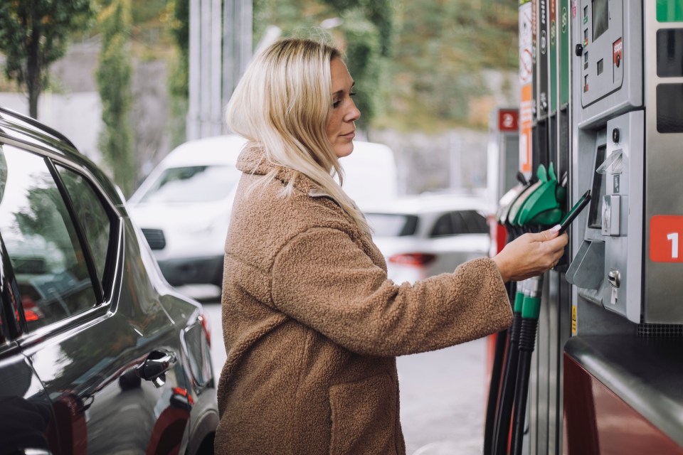 a woman pumps gas into her car at a gas station