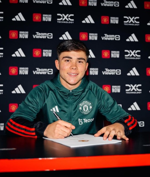 a man in a green manchester united jacket is signing a document