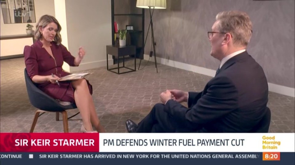 a man and a woman are sitting in front of a screen that says sir keir starmer pm defends winter fuel payment cut