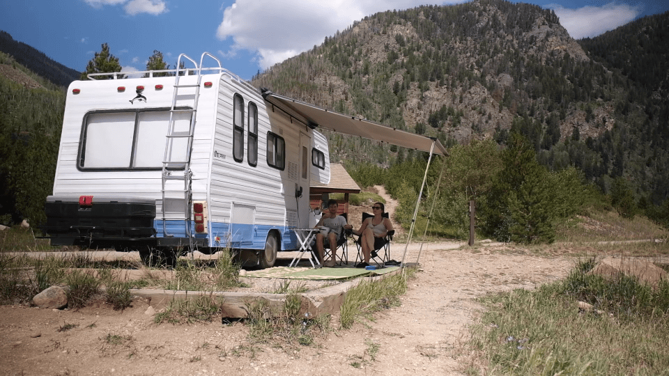 a white and blue rv is parked in the mountains