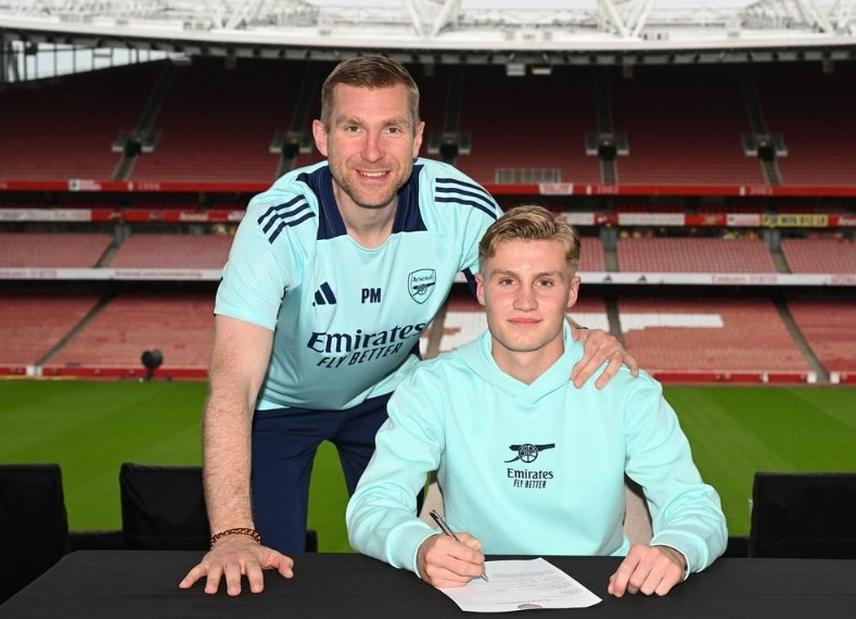 a man in an emirates fly better shirt stands next to a young man