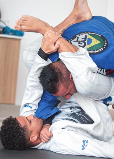 a man wearing a hawk jiu jitsu uniform holds another man 's leg