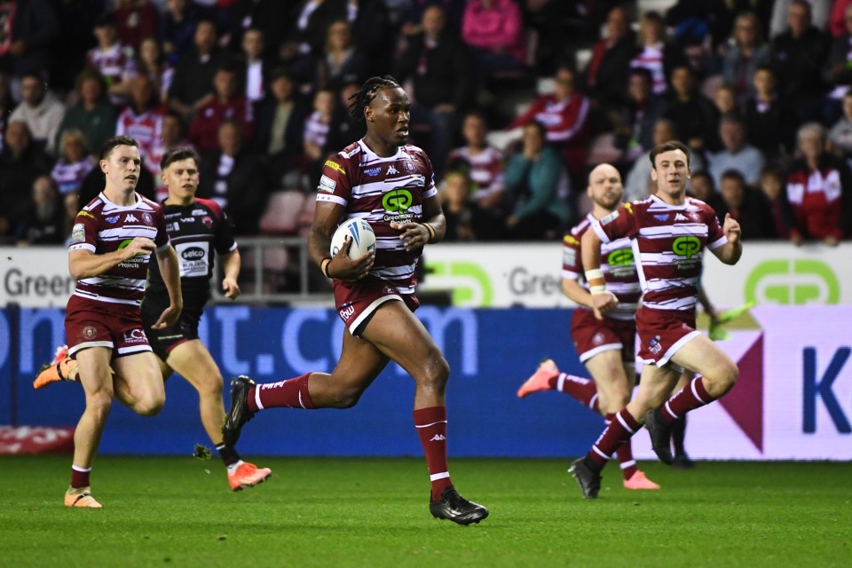 a group of rugby players are running on a field sponsored by green energy