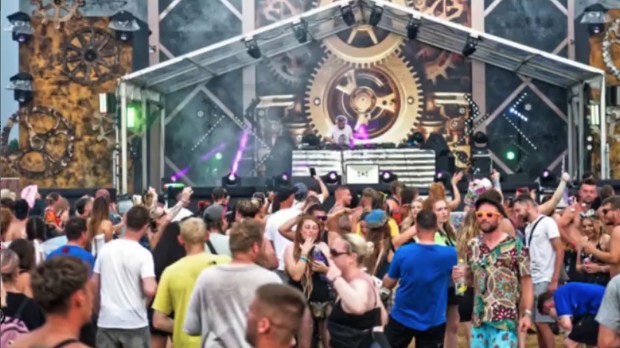 a crowd of people are dancing in front of a stage with gears on it