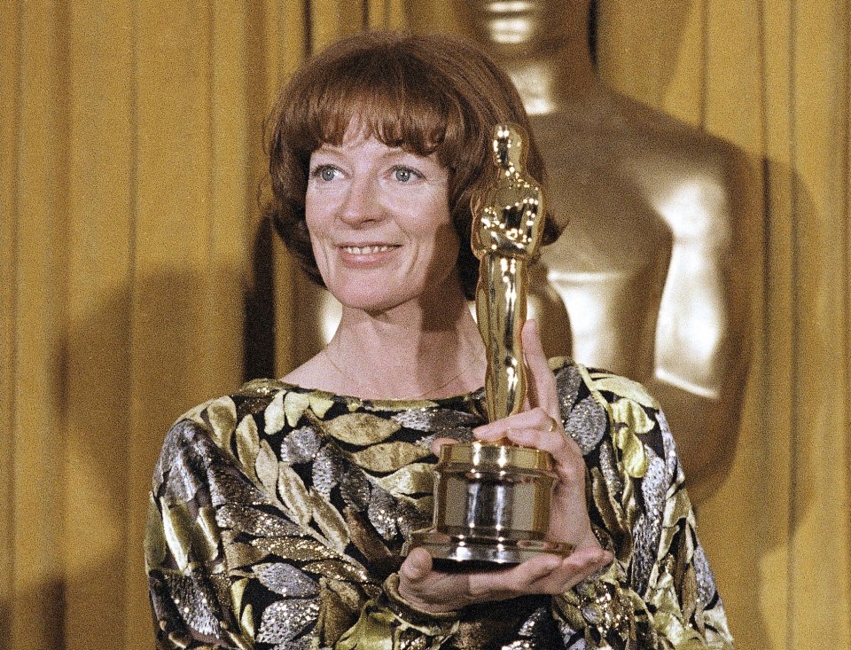 a woman in a gold and silver dress is holding an oscar statue