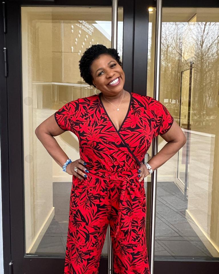 a woman in a red jumpsuit stands in front of a glass door